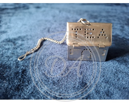 Stainless steel tea strainer and insert in the shape of a house.